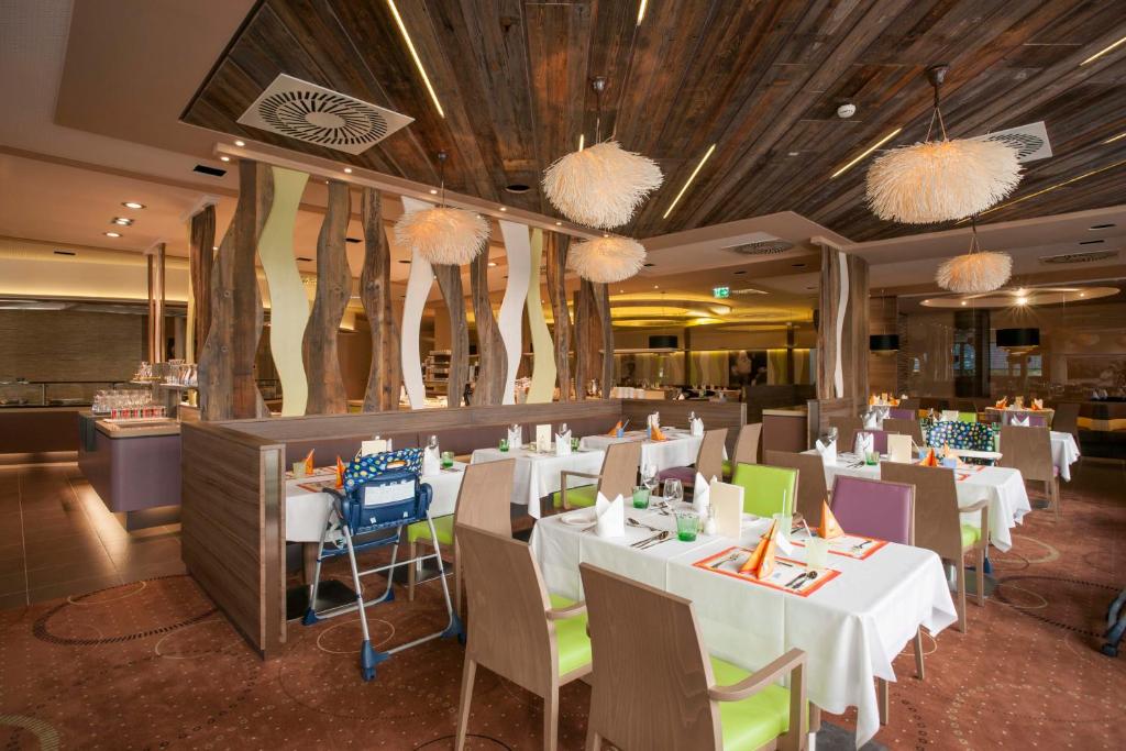 ein Restaurant mit weißen Tischen, Stühlen und Kronleuchtern in der Unterkunft Allegria Resort Stegersbach - Allegria Hotel in Stegersbach