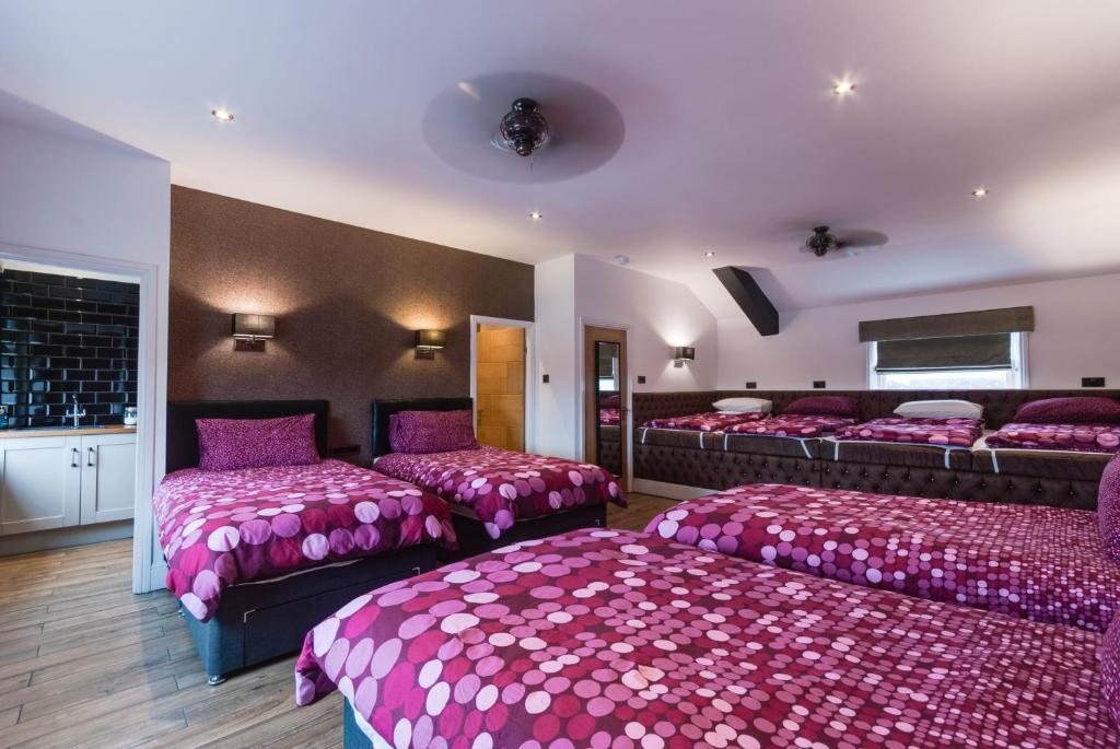 um quarto com 4 camas com lençóis e almofadas cor-de-rosa em Tom Thumb Apartments em Liverpool