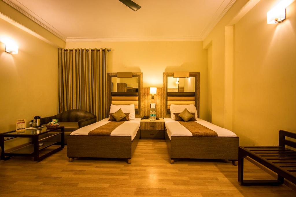 ニューデリーにあるザ サンコート ホテル ヤトリのベッド2台とソファが備わるホテルルームです。