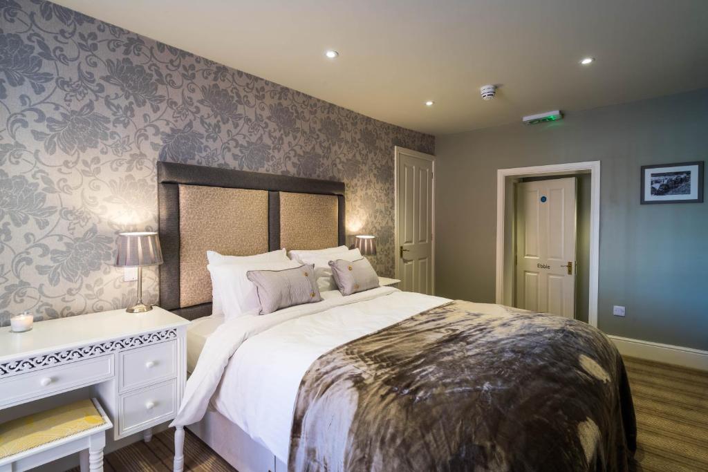 a bedroom with a large bed and a desk at Greyhound Inn Wilton in Salisbury