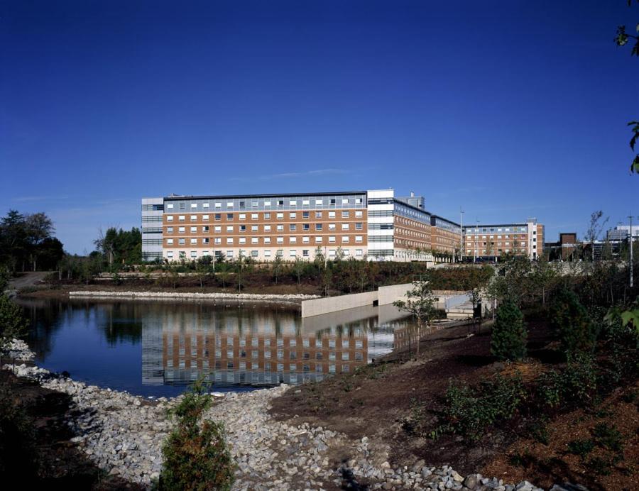 un edificio con un reflejo en un cuerpo de agua en Residence & Conference Centre - Oshawa en Oshawa