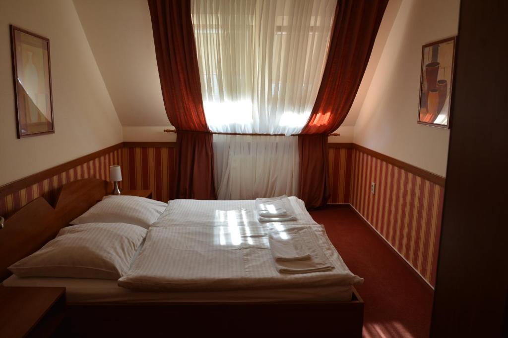 a bedroom with a bed and a window with a curtain at Penzion na Potočnej in Skalica