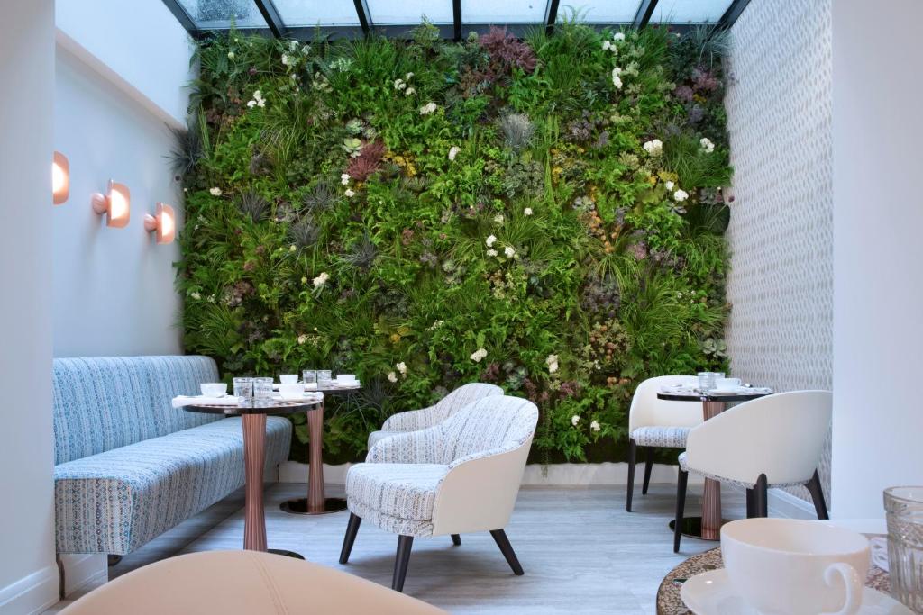 zielony mur ze stołami i krzesłami w restauracji w obiekcie Hôtel Dress Code w Paryżu