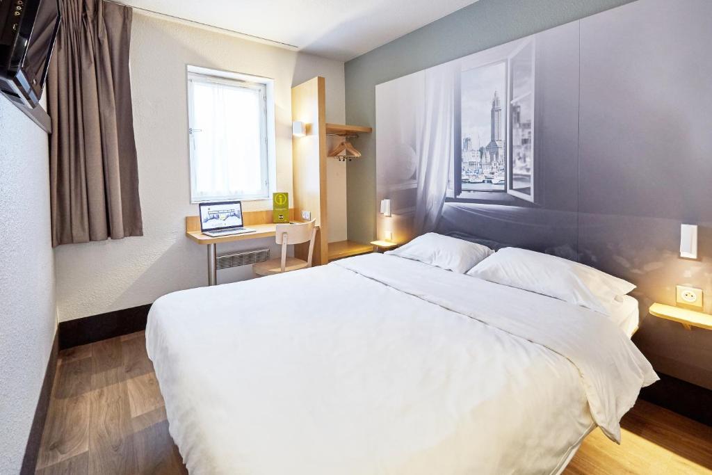 una camera d'albergo con un grande letto bianco e una finestra di B&B HOTEL Le Havre Harfleur 2 a Harfleur
