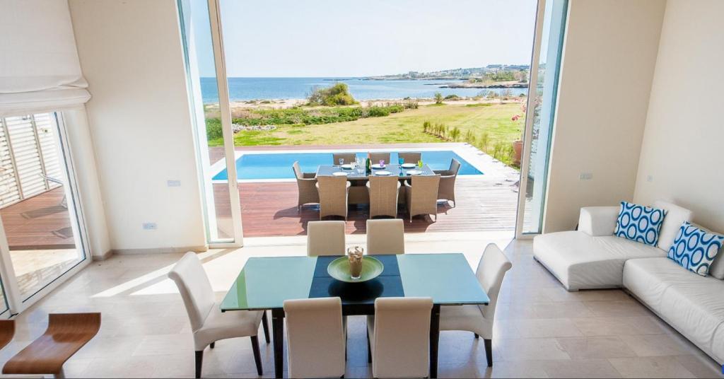 a dining room with a table and chairs and a pool at Luxury Bay View Villa 20 Right On Τhe Beach in Protaras