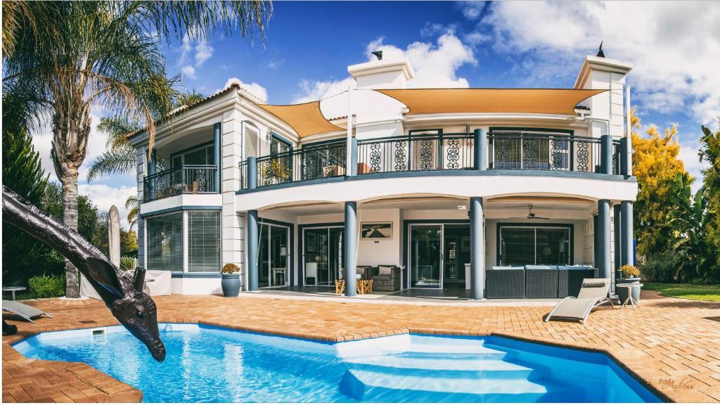 a house with a swimming pool in front of it at Pictures Guest House Boutique Hotel in Oudtshoorn