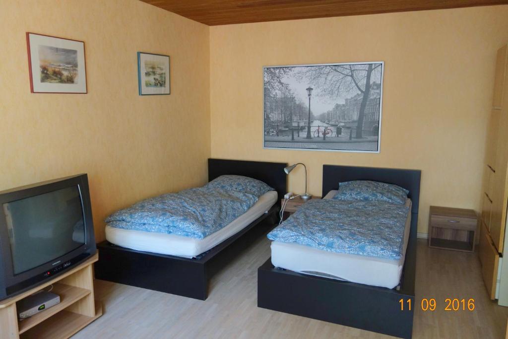 two beds in a room with a tv and a tv at Haus Weschke in Hofheim am Taunus