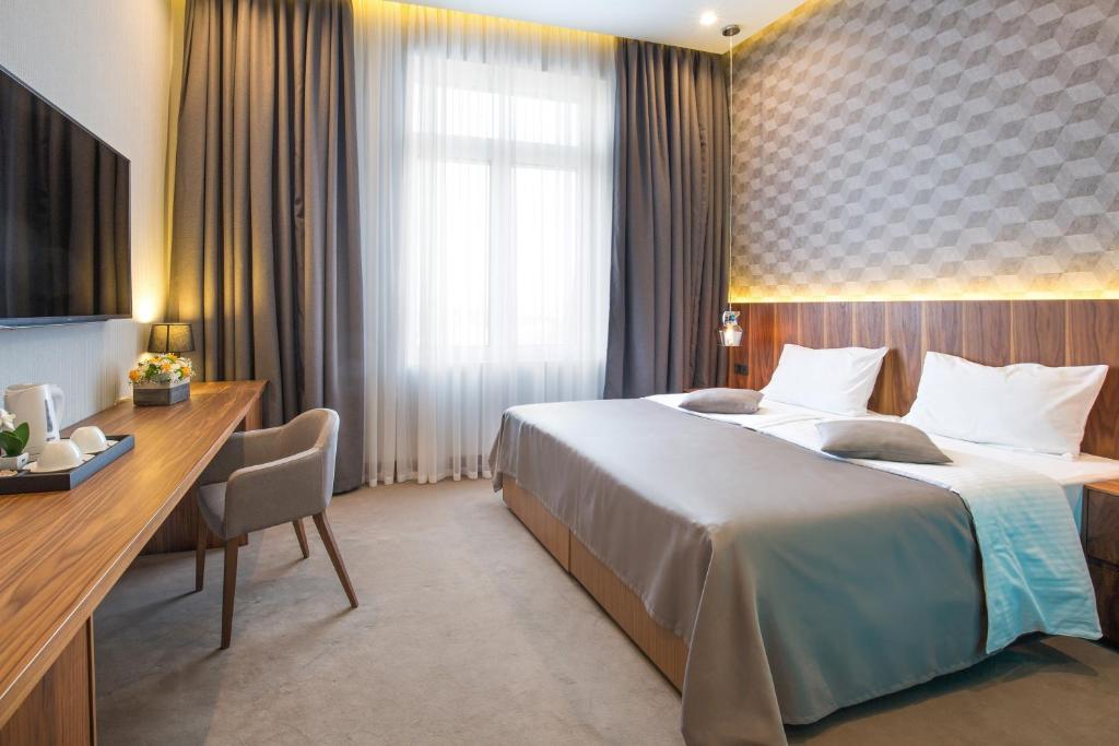 a hotel room with a large bed and a desk at Five Points Square - City Center in Belgrade