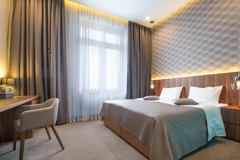 a hotel room with a bed and a desk and a window at Five Points Square - City Center in Belgrade