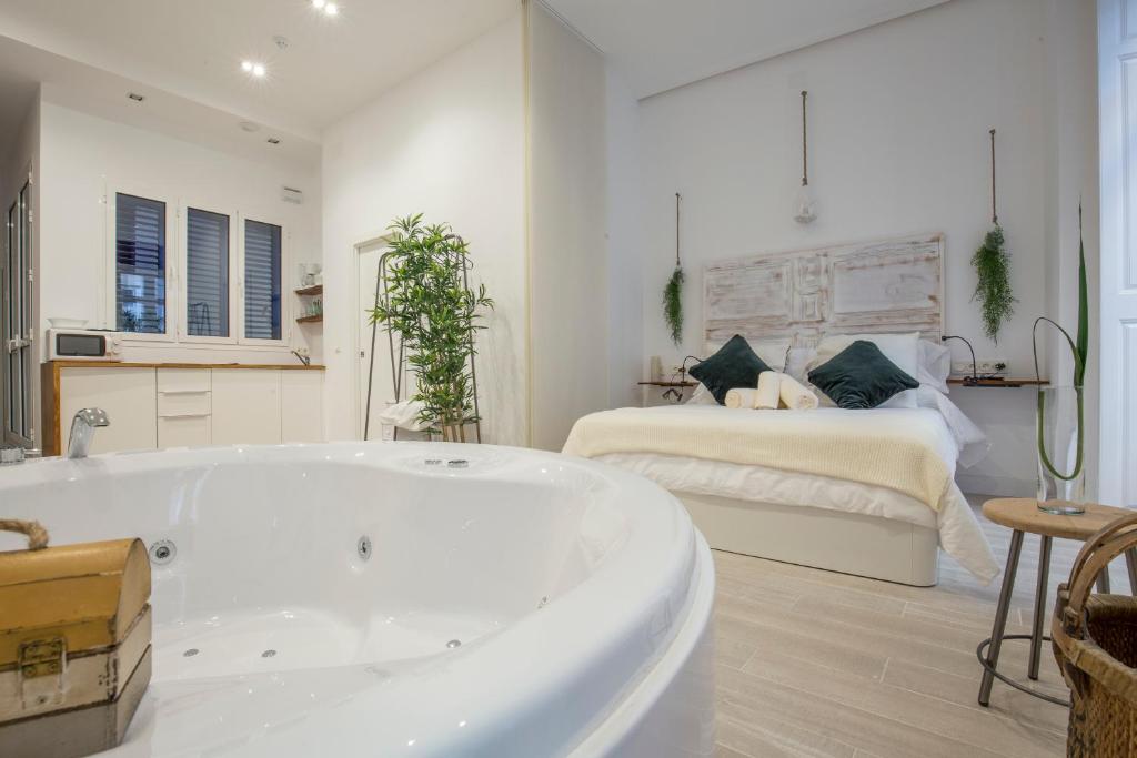 - une baignoire blanche dans une chambre avec un lit dans l'établissement Living4Malaga Skyline Apartments, à Malaga