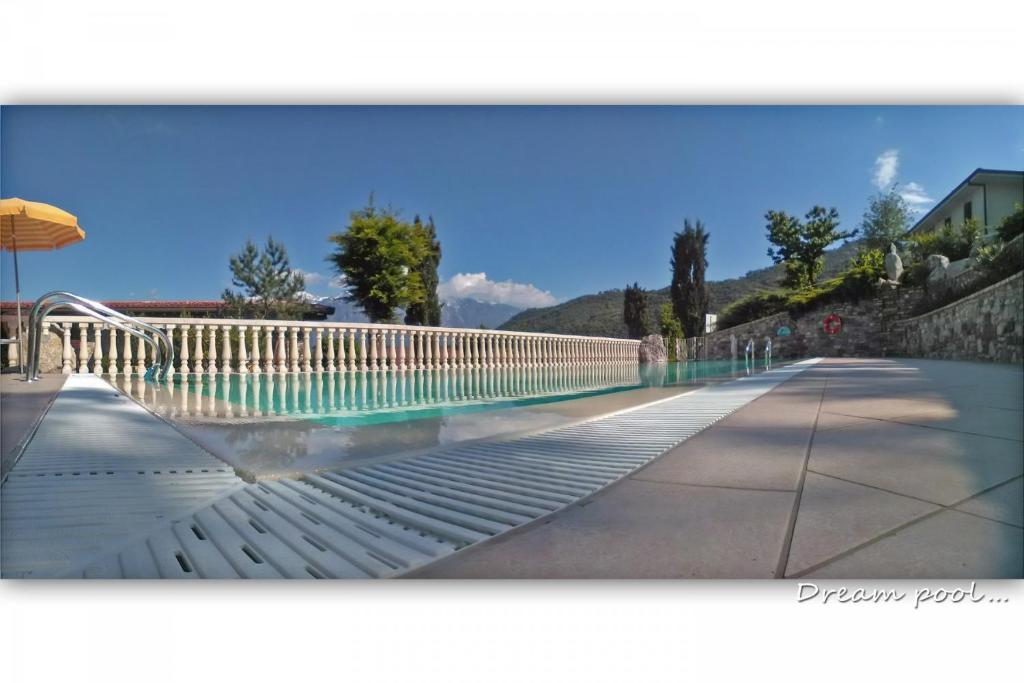 a swimming pool with a fence and an umbrella at Appartamenti La Tartufaia Country house pool and relax By Gardadomusmea in Tremosine Sul Garda
