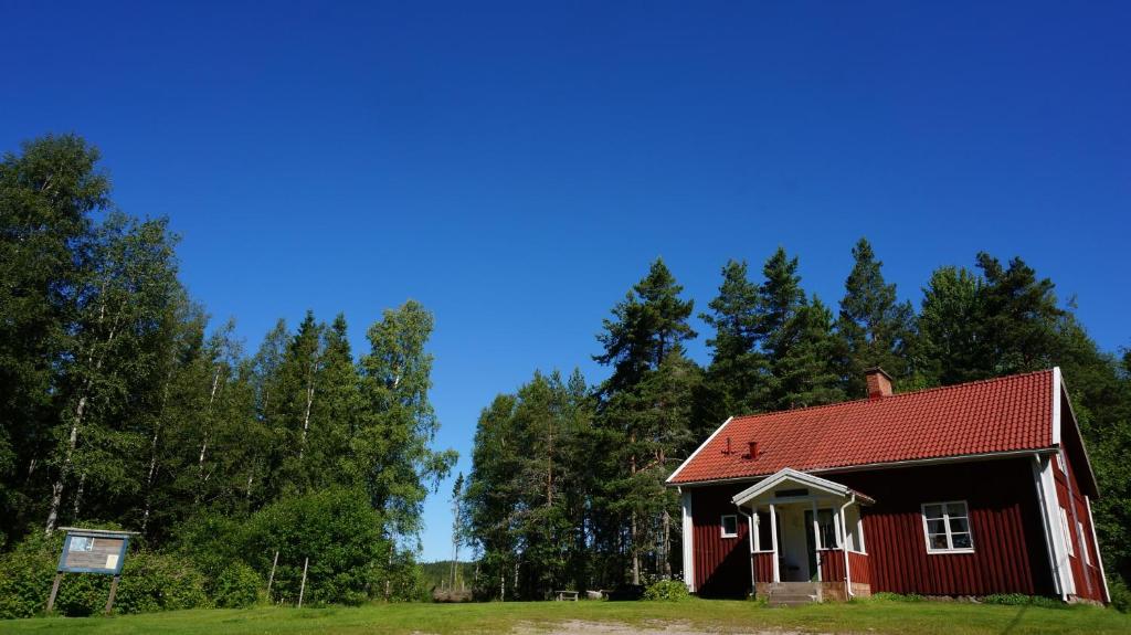 a red house with a red roof in a field at Björnvålsfallet in Deje