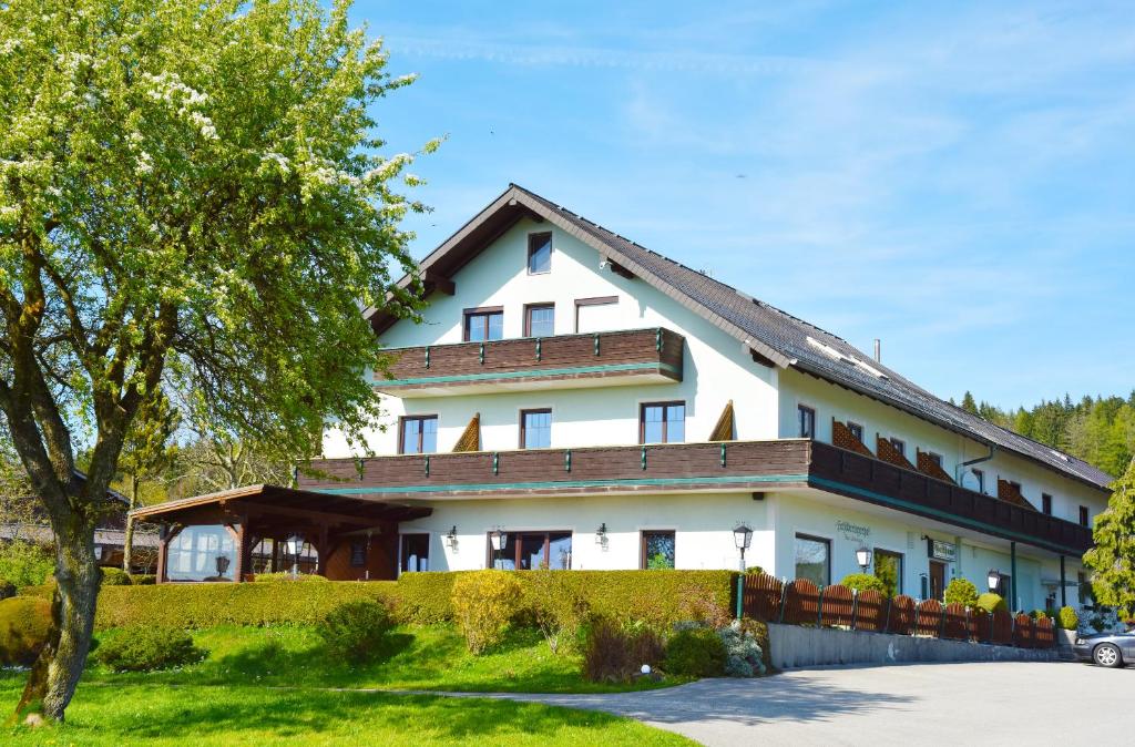 ein großes weißes Gebäude mit einem Zaun und einem Baum in der Unterkunft Gasthaus Schöberingerhof in Weyregg