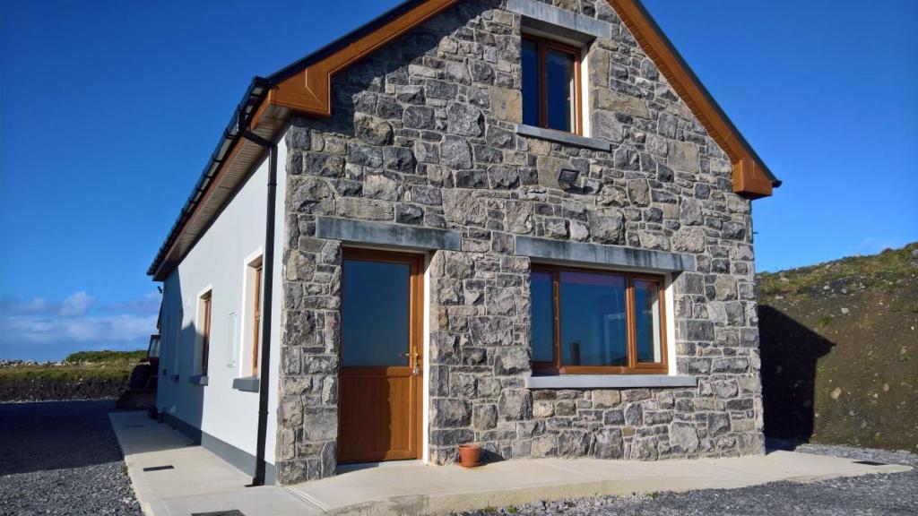 a stone house with a brown door and windows at Doolin Heights Apartment in Doolin