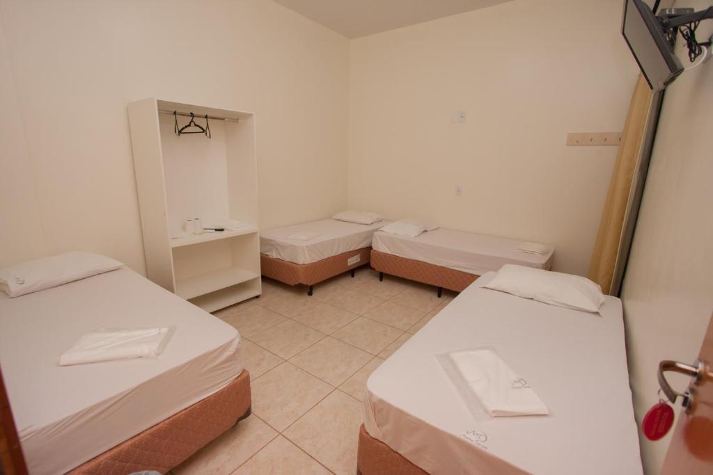 a small room with three beds and a sink at Hotel Marina Torrano in Trindade