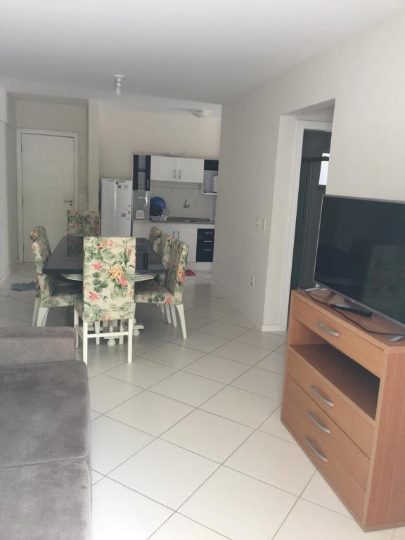 sala de estar con sofá y TV y cocina en Apartamento de 2 quartos no Jardim das Américas- Bombinhas, en Bombinhas