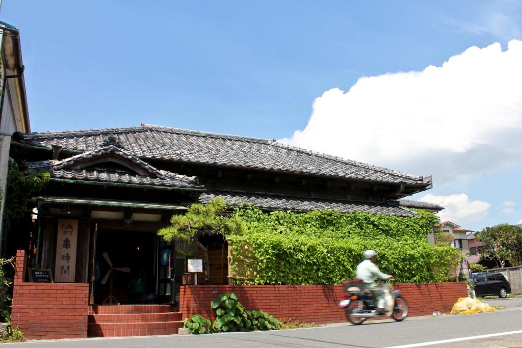 mężczyzna jeżdżący motocyklem przed budynkiem w obiekcie Guest House Kamejikan -turtle time- w mieście Kamakura