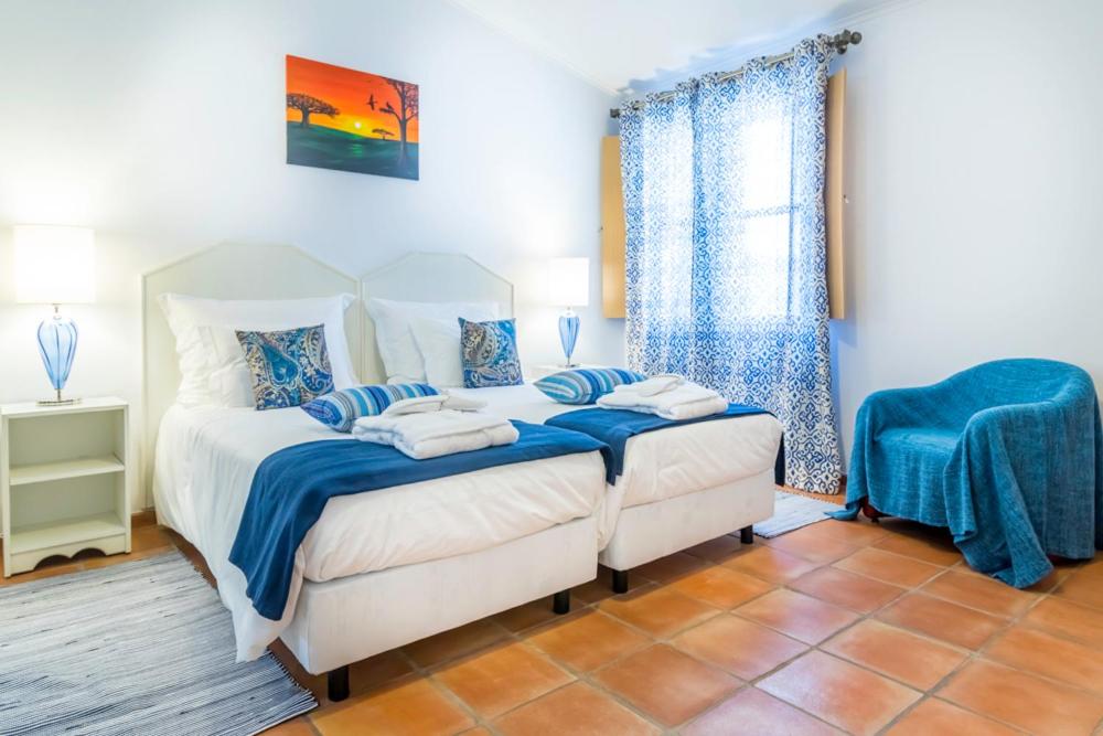 - une chambre avec un lit doté de draps bleus et une fenêtre dans l'établissement Abetarda CC, à São Marcos da Ataboeira