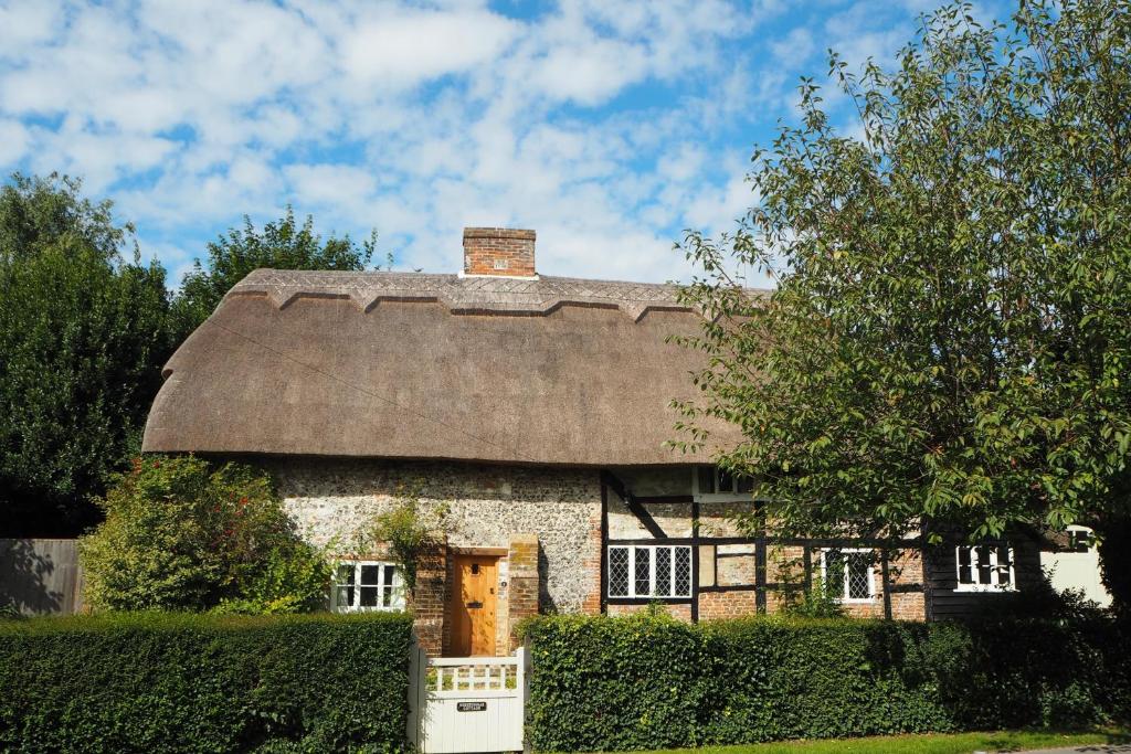 an old stone house with a thatched roof at Nightingale Cottage Bed and Breakfast in Chichester