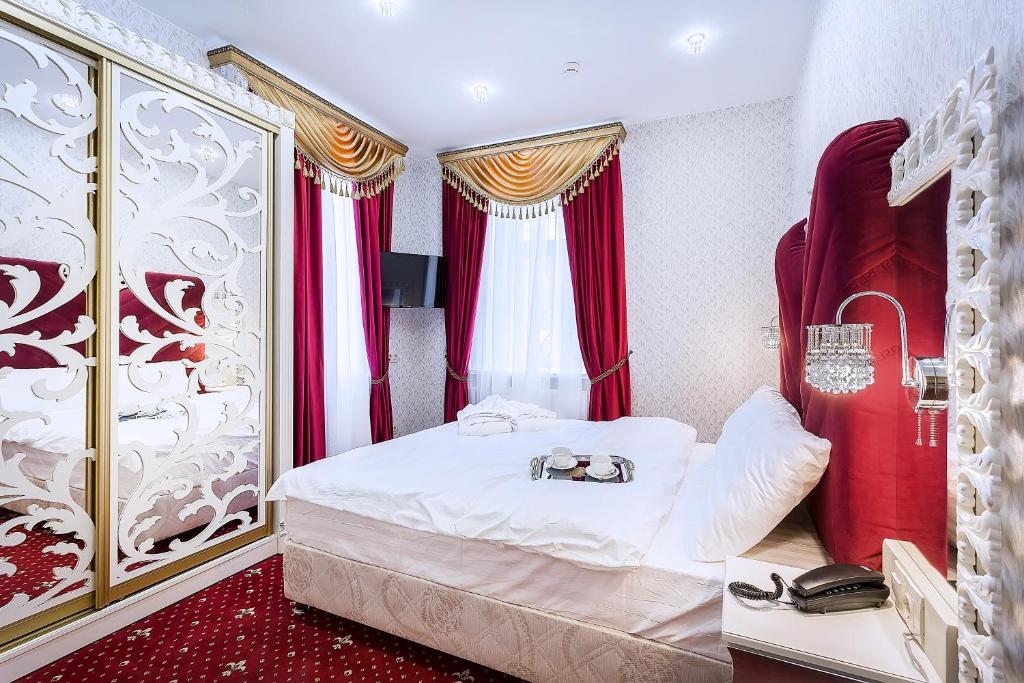 モスクワにあるОтель Сан-Ремоのベッドルーム(赤いカーテン付きの白いベッド1台付)