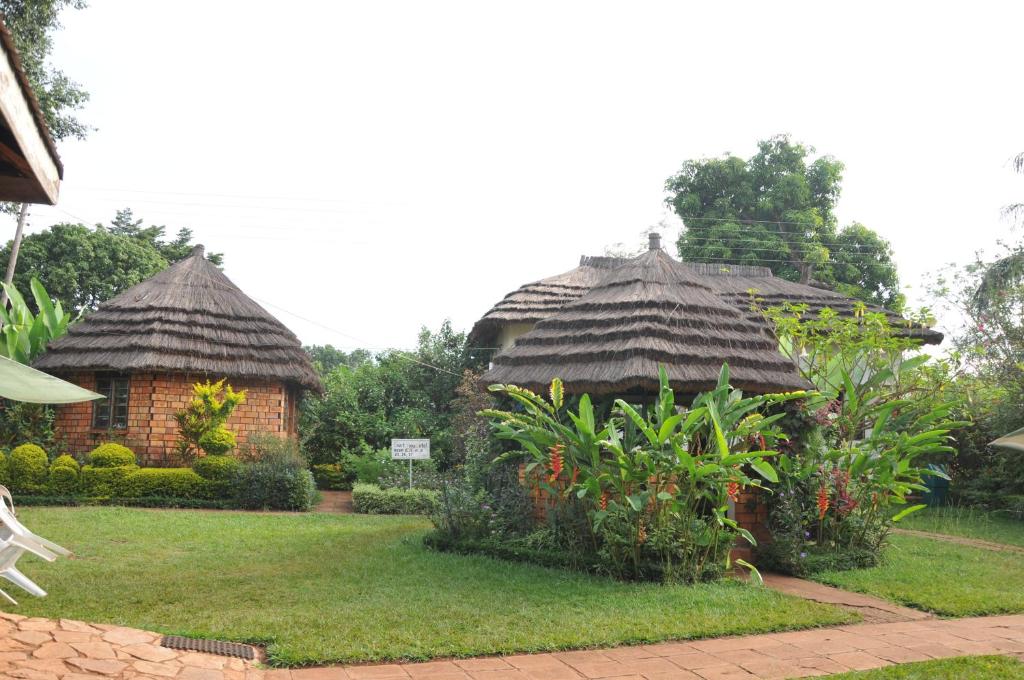 two huts with thatched roofs in a yard at New Court View Hotel in Masindi