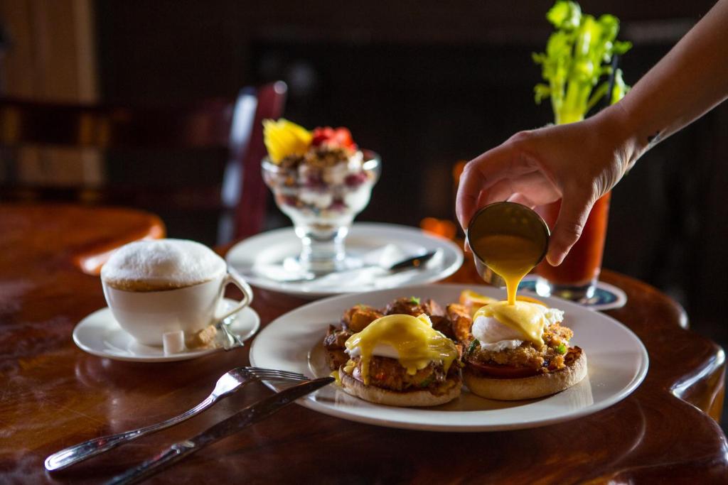 a person drizzling mustard on two pancakes with coffee at McMenamins Gearhart Hotel in Gearhart