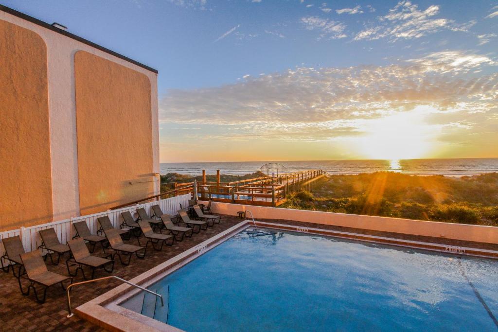 un hotel con piscina, sillas y el océano en Beacher's Lodge en Crescent Beach
