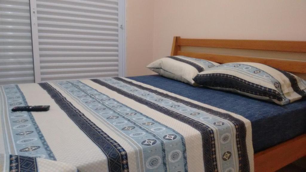 ein Schlafzimmer mit einem Bett mit zwei Kissen darauf in der Unterkunft Guerreiro Sui­tes in Boicucanga