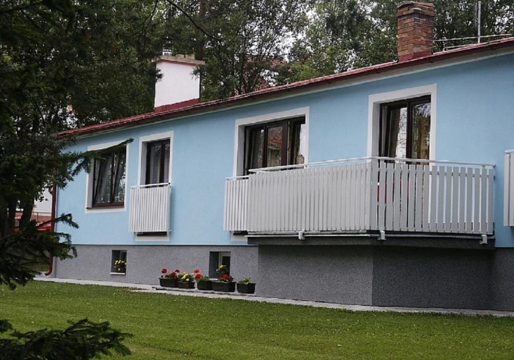 ein blaues Haus mit weißen Balkonen und roten Blumen in der Unterkunft Penzion Jája Lipno nad Vltavou in Lipno nad Vltavou