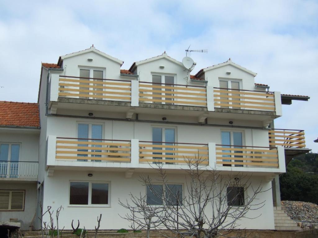 a large white building with wooden balconies at Apartmani Ivan in Kaprije