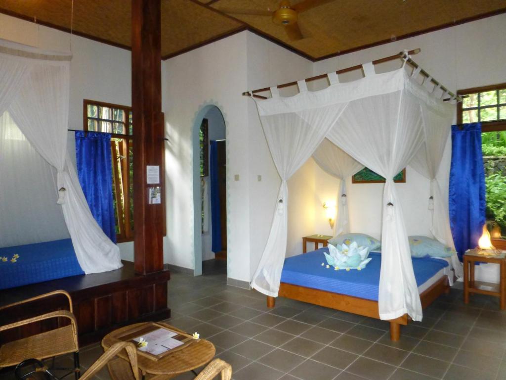 Schlafzimmer mit einem blauen Bett und Moskitonetzen in der Unterkunft Sananda Bungalow in Lovina