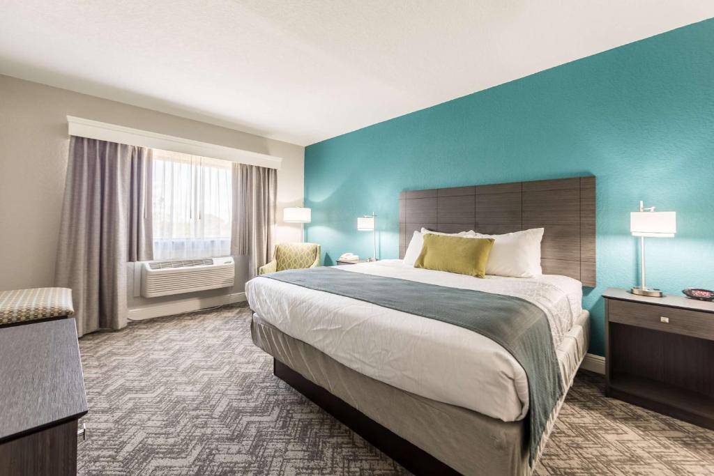 a bedroom with a large bed and a blue wall at Best Western Plus Sebastian Hotel & Suites in Sebastian