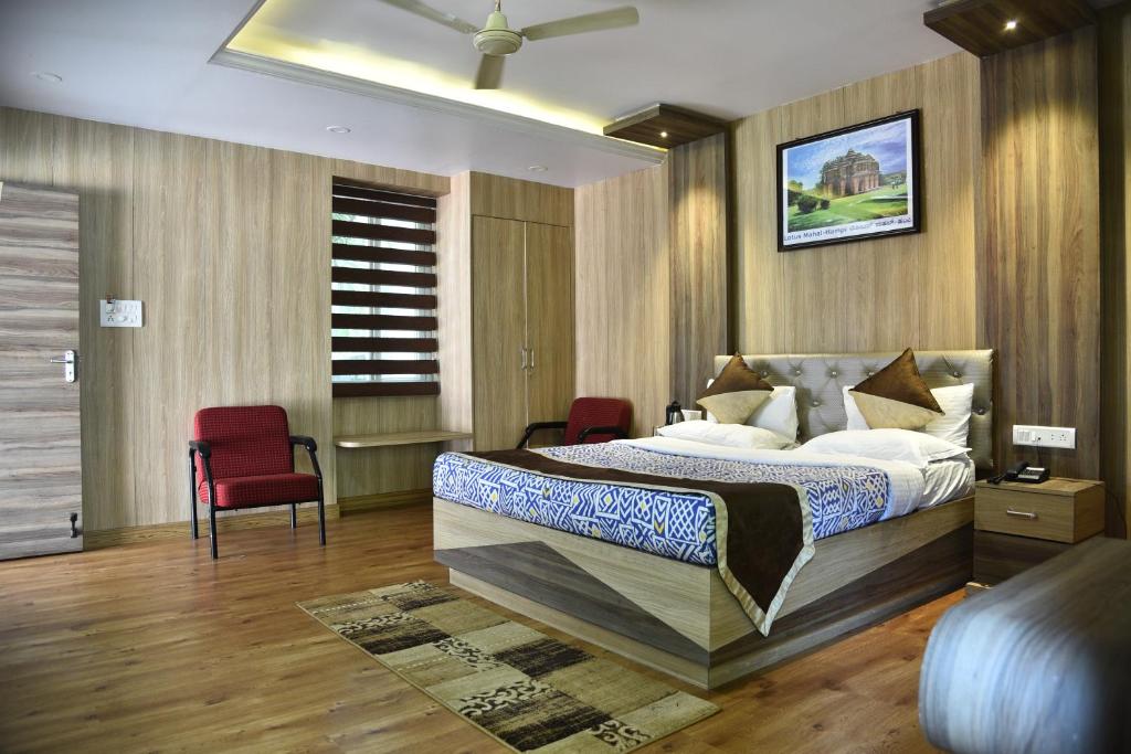 a bedroom with a bed and two red chairs at KSTDC Hotel Mayura Riverview Srirangapatna in Seringapatam
