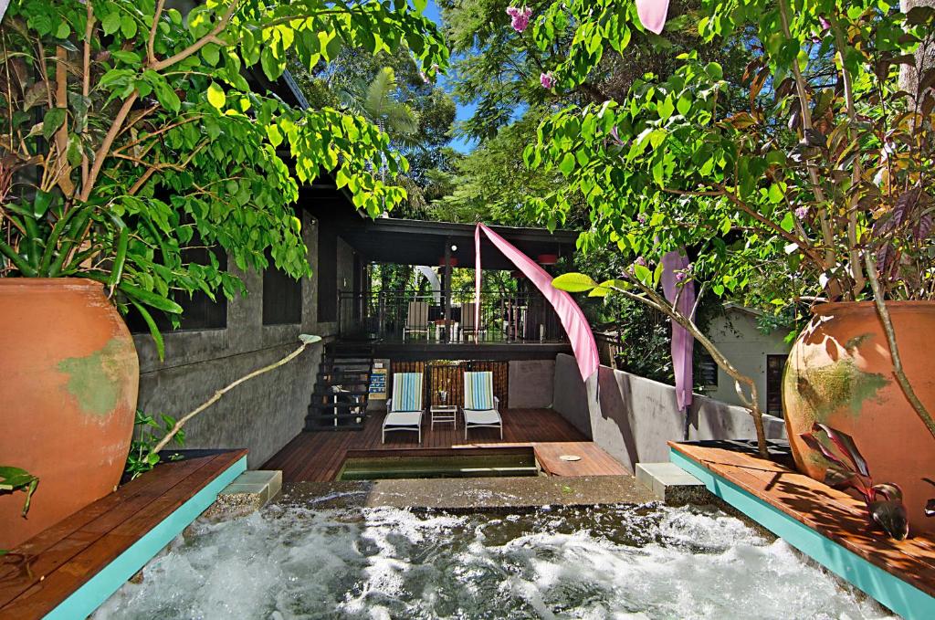 un patio trasero con piscina con cascada y plantas en CELADON Holiday House, en Palm Cove