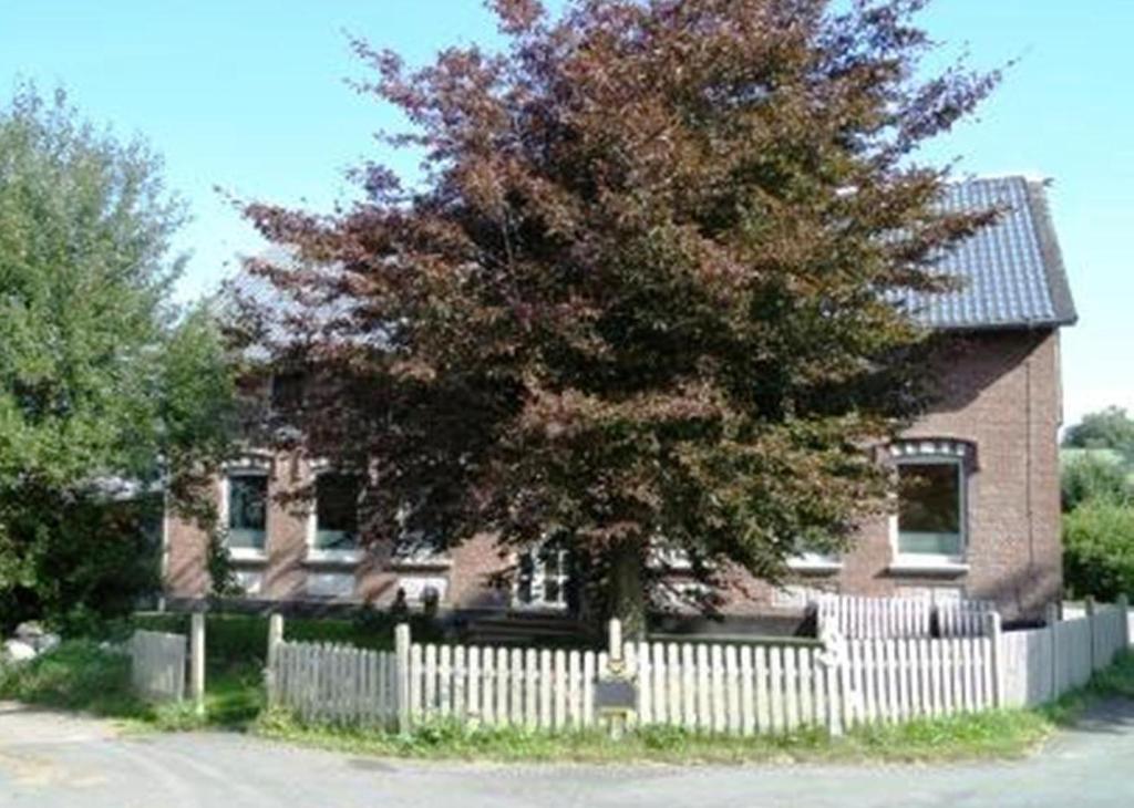 a white fence in front of a house with a tree at Fewo Bendig in Neuendorf-Sachsenbande