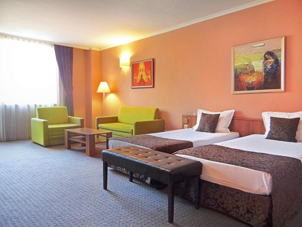 una camera d'albergo con due letti e una sedia di Hotel Real a Plovdiv