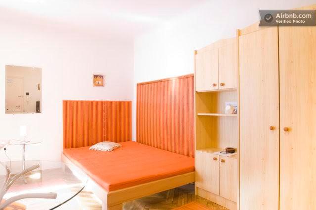ブダペストにあるGold Apartmentのオレンジ色のベッドとキャビネットが備わる小さな客室です。