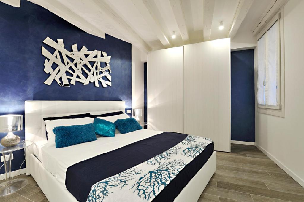 1 dormitorio con cama blanca y pared azul en Ca Forner - Cannaregio Apartment, en Venecia