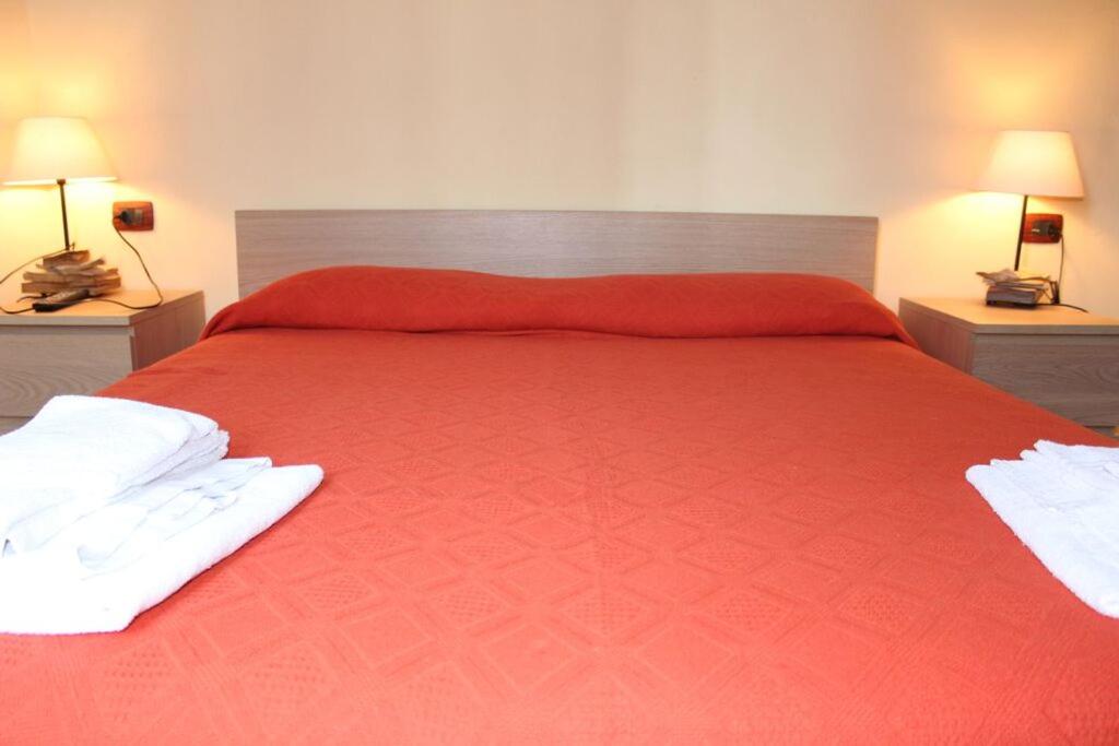 Un dormitorio con una cama roja con toallas blancas. en La Pergola, en Zibido San Giacomo