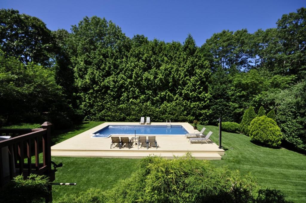 una piscina en un patio con 2 sillas en Nice 4bdr all Q size,IG Pool,Billiard, en Hampton Bays