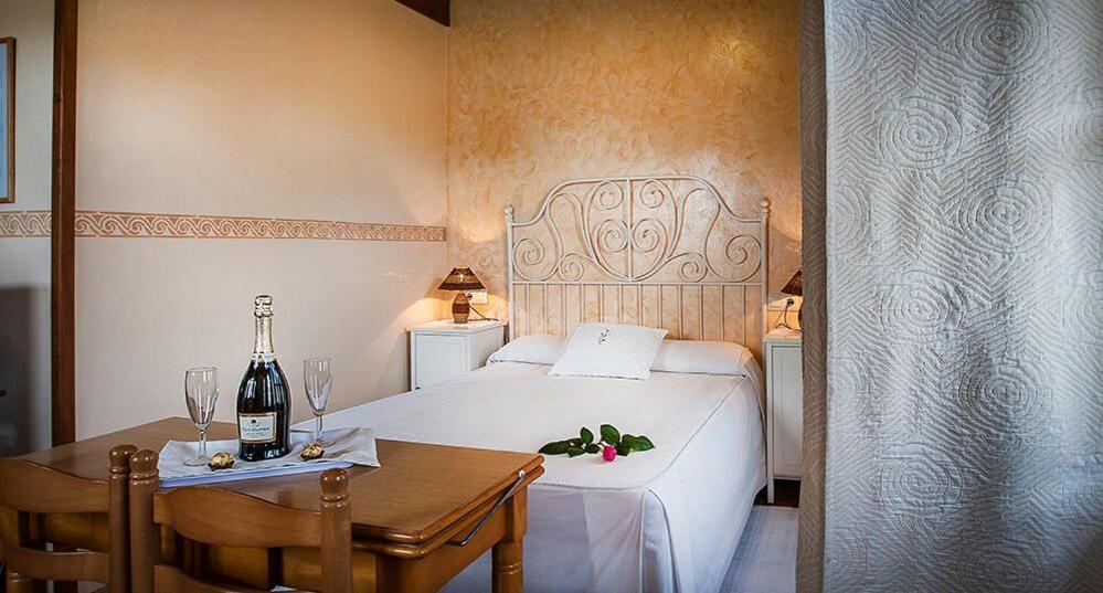 Un dormitorio con una cama y una mesa con una botella de vino en Apartamentos El Pradón de Santa Marina, en Parres de Llanes