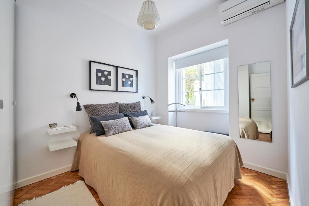 Dormitorio blanco con cama y ventana grande en Casa Oliveira in Alvalade, en Lisboa