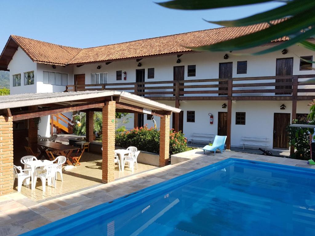 une terrasse avec une piscine et une maison dans l'établissement Vargas Peruibe Hotel, à Peruíbe