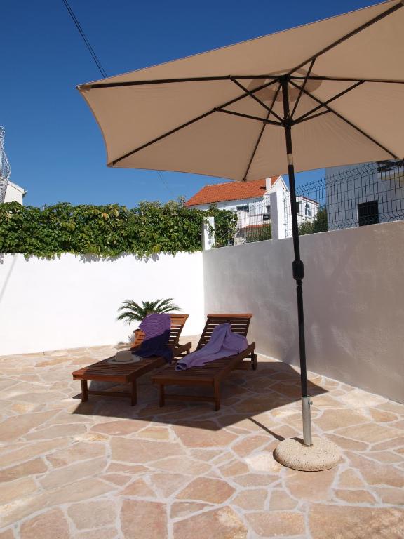 two chairs and an umbrella on a patio at Apartment Lux Star in Milna