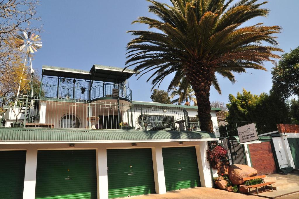 a building with green garage doors and a palm tree at Agterplaas Guesthouse in Johannesburg