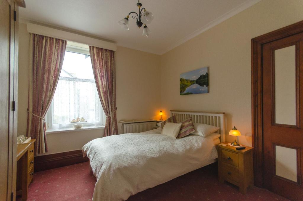 1 dormitorio con 1 cama con 2 lámparas y una ventana en Abacourt House, en Keswick