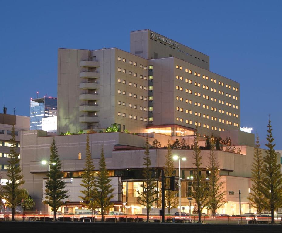 um grande edifício com árvores em frente em Sendai Kokusai Hotel em Sendai