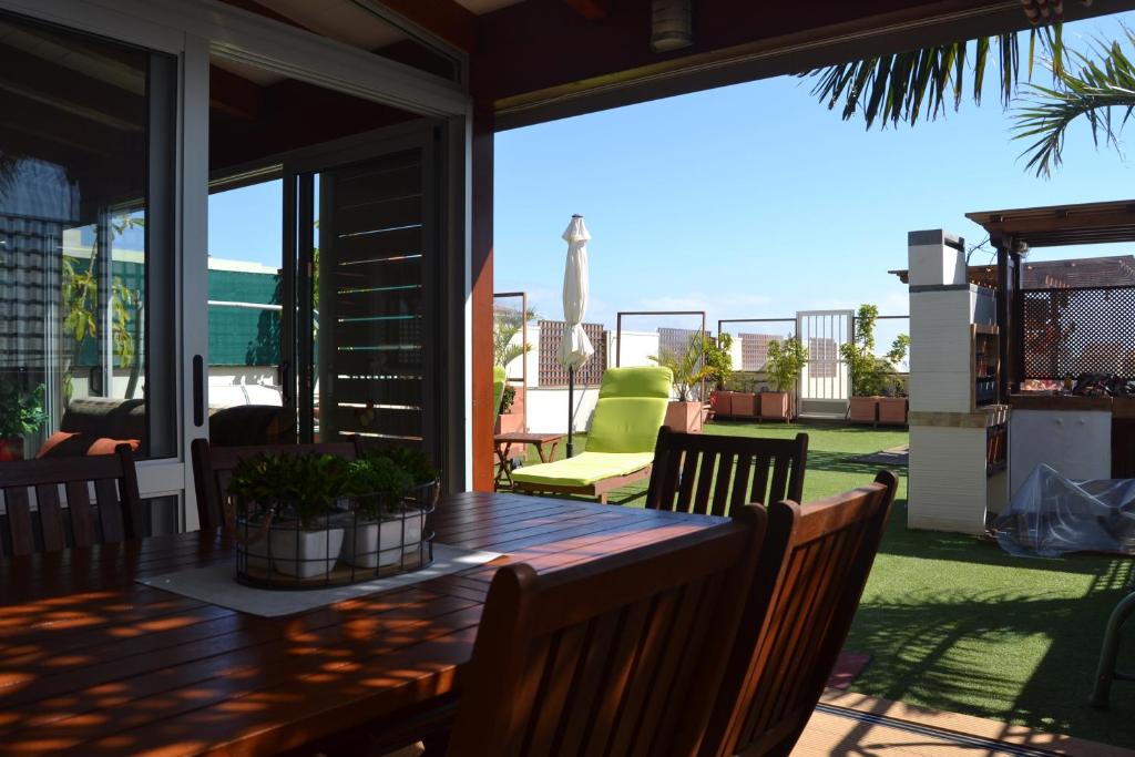 a deck with a wooden table and chairs on a patio at Apartamento Vacacional Ático frente al mar in Candelaria