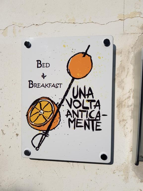 una señal colgada en una pared con una naranja en Una Volta Anticamente, en Cascinette