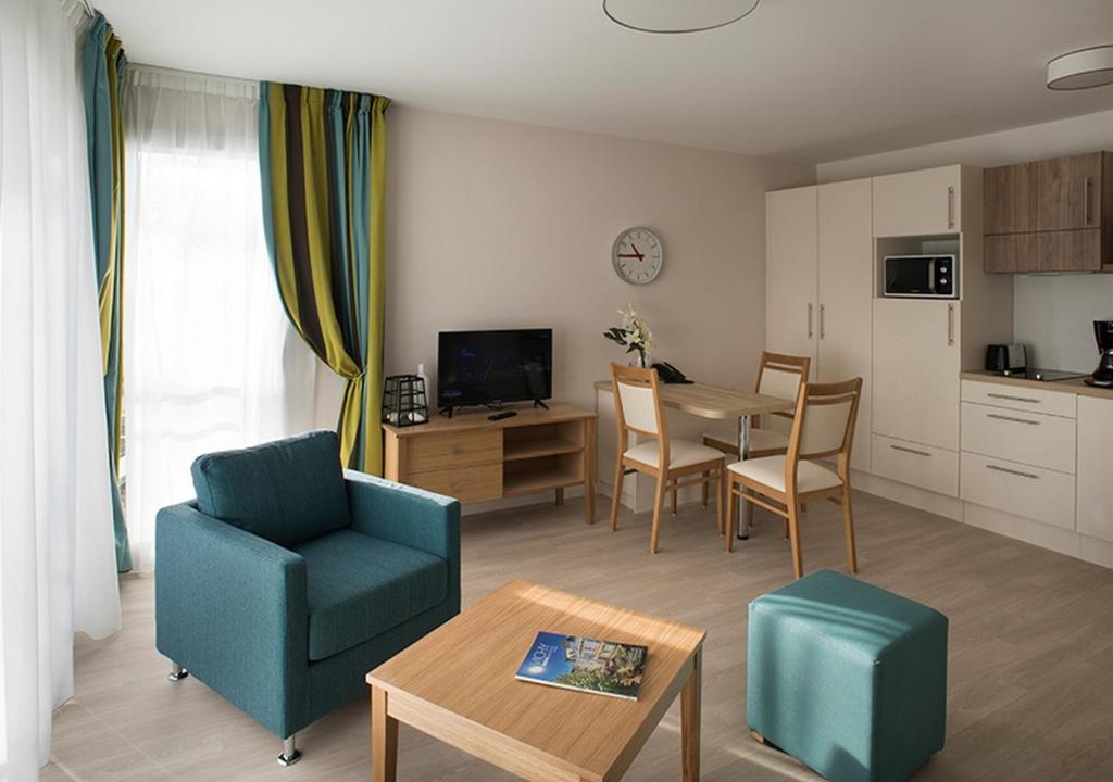 a living room with a table and chairs and a kitchen at Domitys La Fontaine du Roy in Vichy